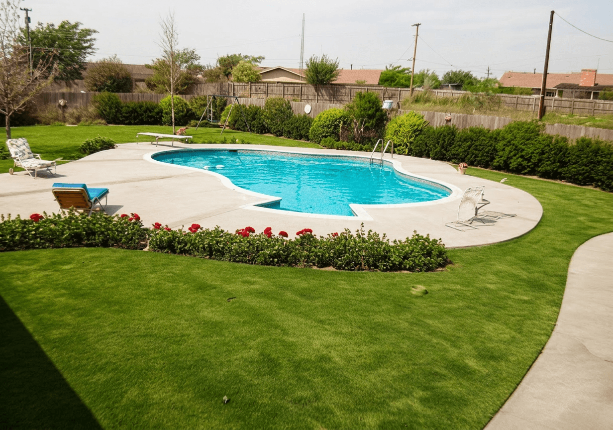 Freeform lagoon-style pool with diving board and curved concrete deck framed by green lawn and shrubs