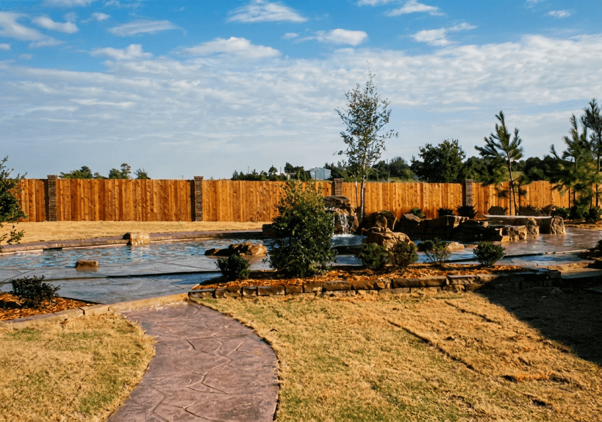 Freeform lagoon-style pool with boulder accents and winding stone walkway across sodded backyard at golden hour
