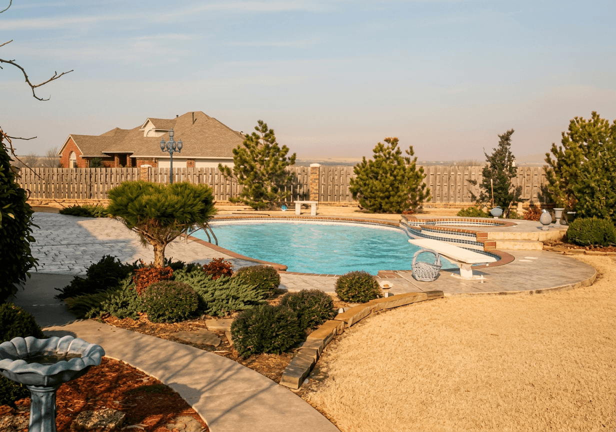Freeform backyard pool with curved diving board, landscaped beds and gravel patio in warm golden-hour light