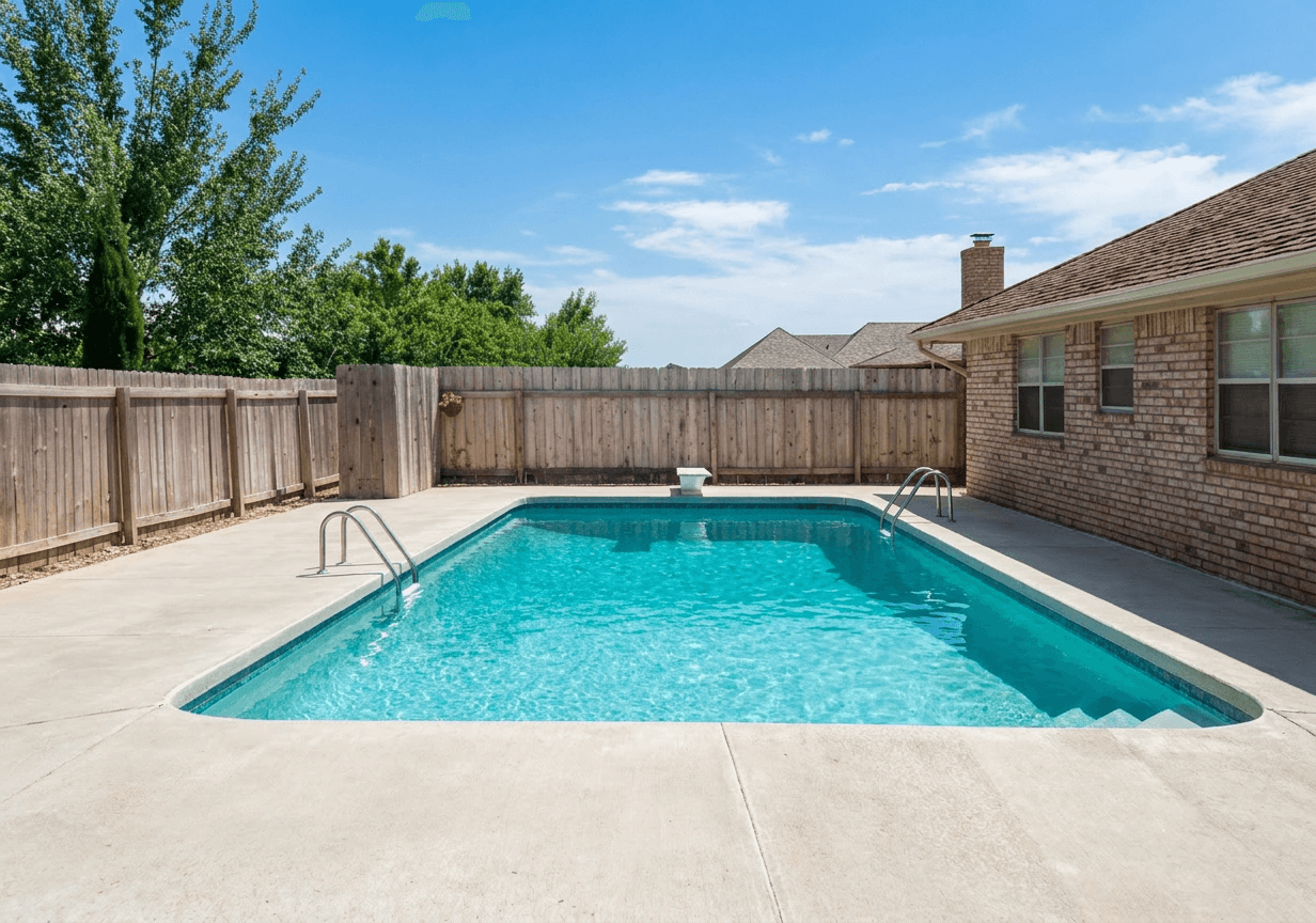 Rectangular in-ground pool with curved corners beside a brick home in a fenced suburban backyard